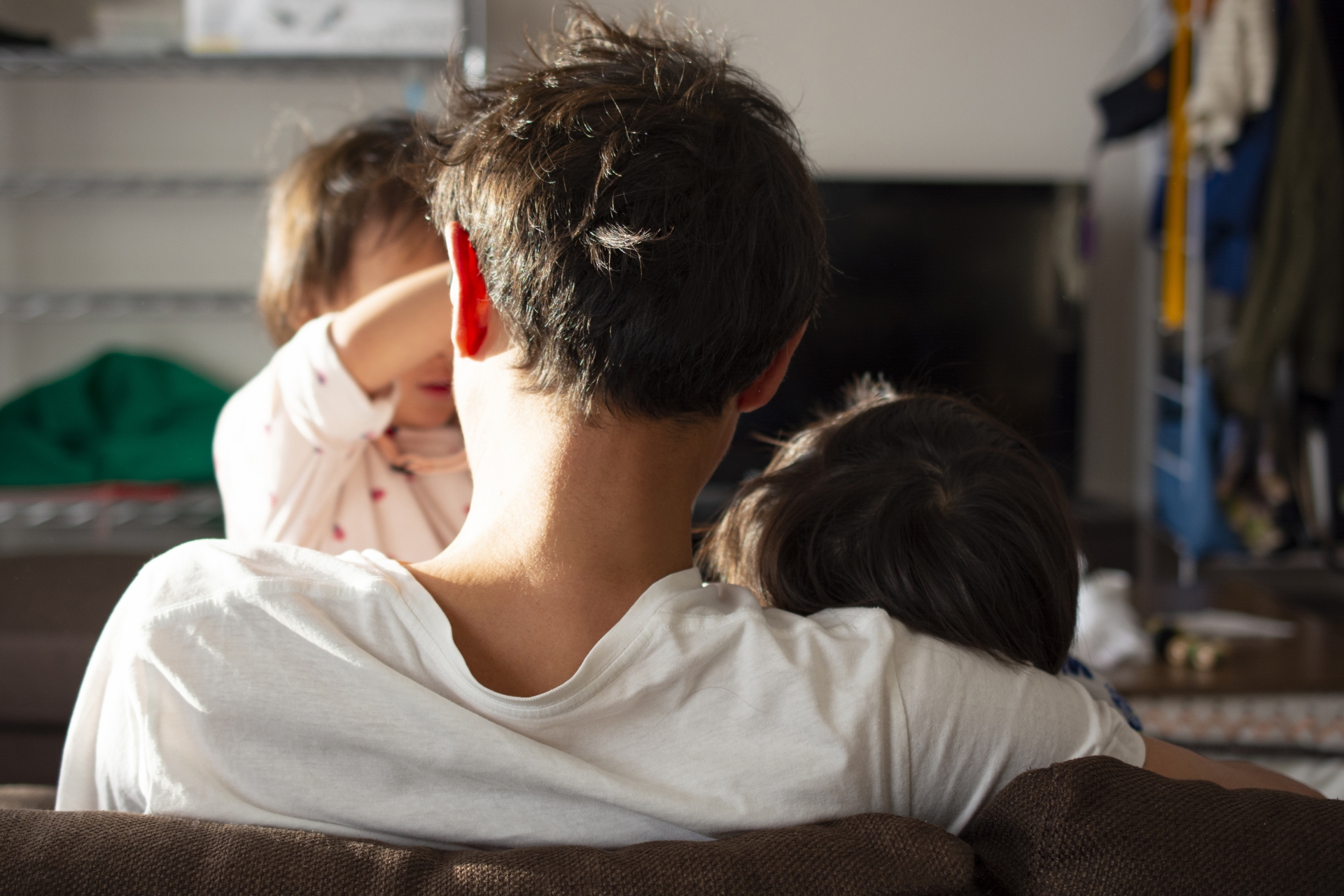 2人の子どもとたわむれる父親の背中